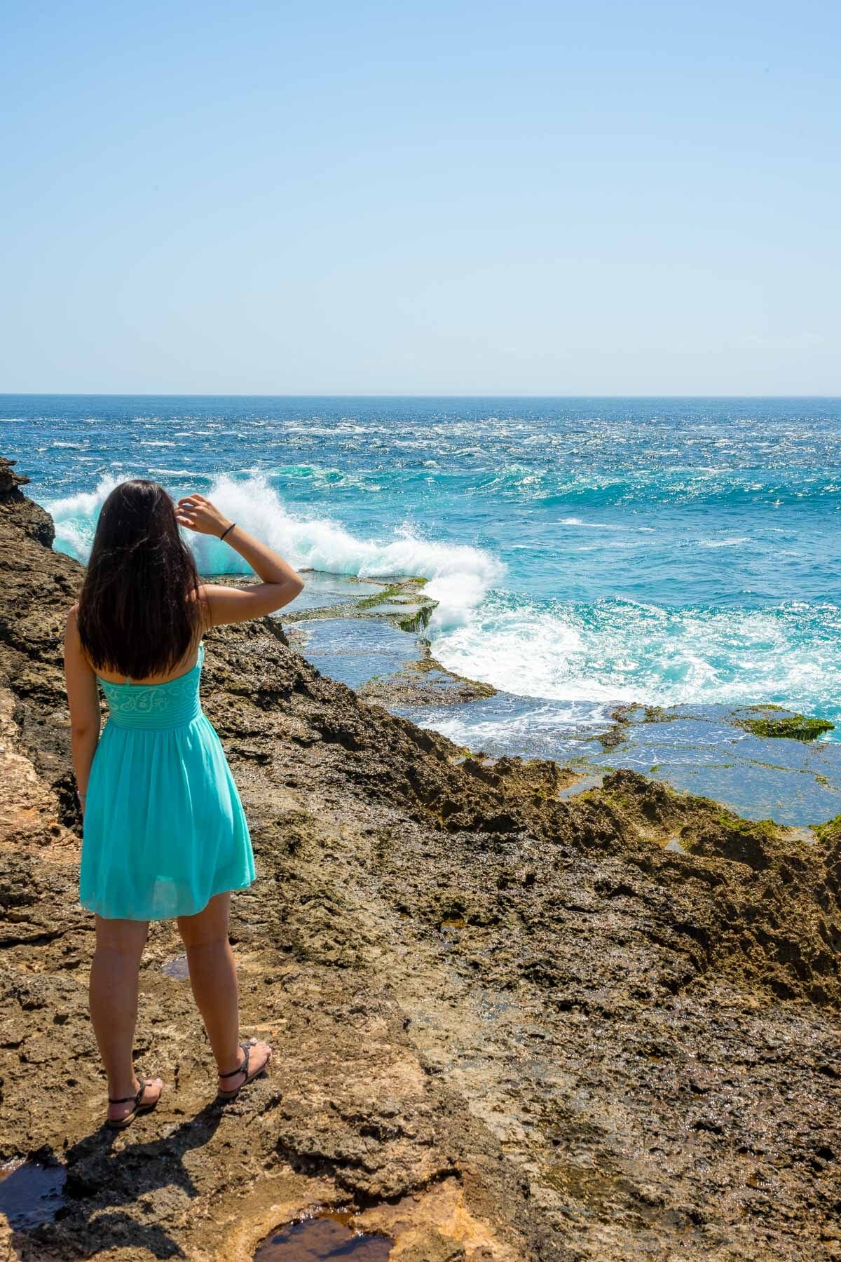 Girl in a blue dress standing at Devils Tear on Nusa Lembongan