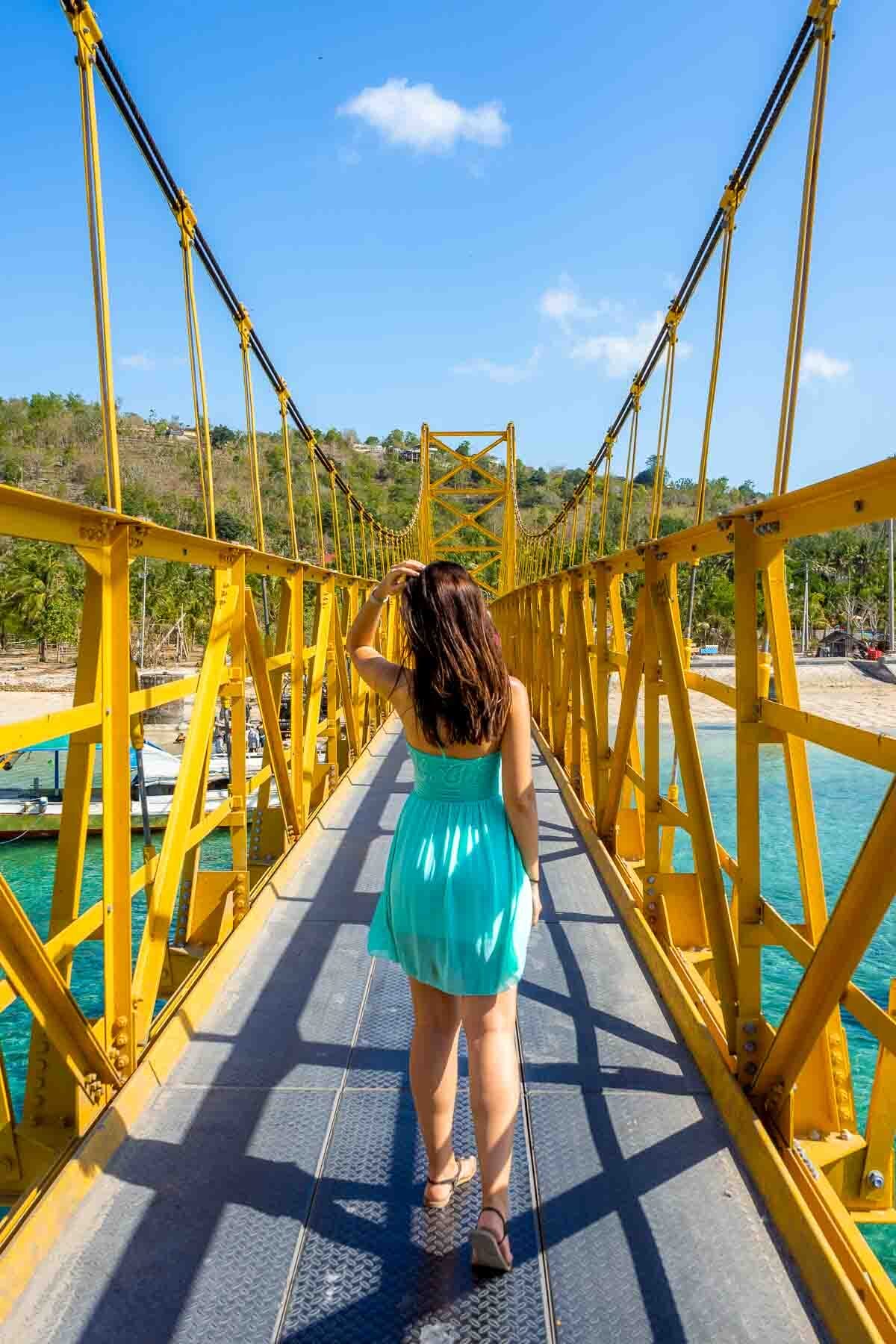 Girl in a blue dress standing on the Yellow bridge between Nusa Lembongan and Nusa Ceningan