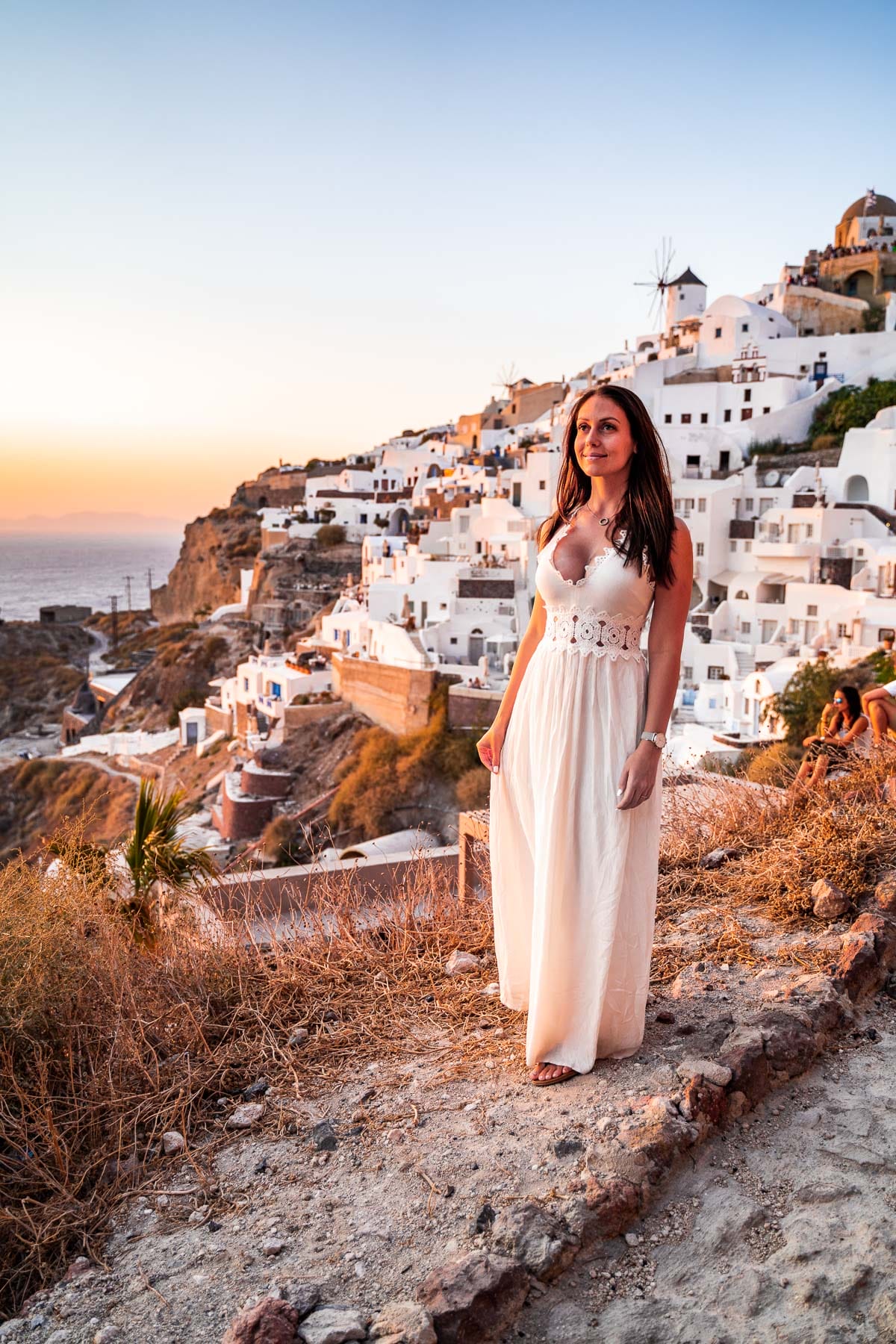 Girl in a white dress watching the sunset in Oia, Santorini