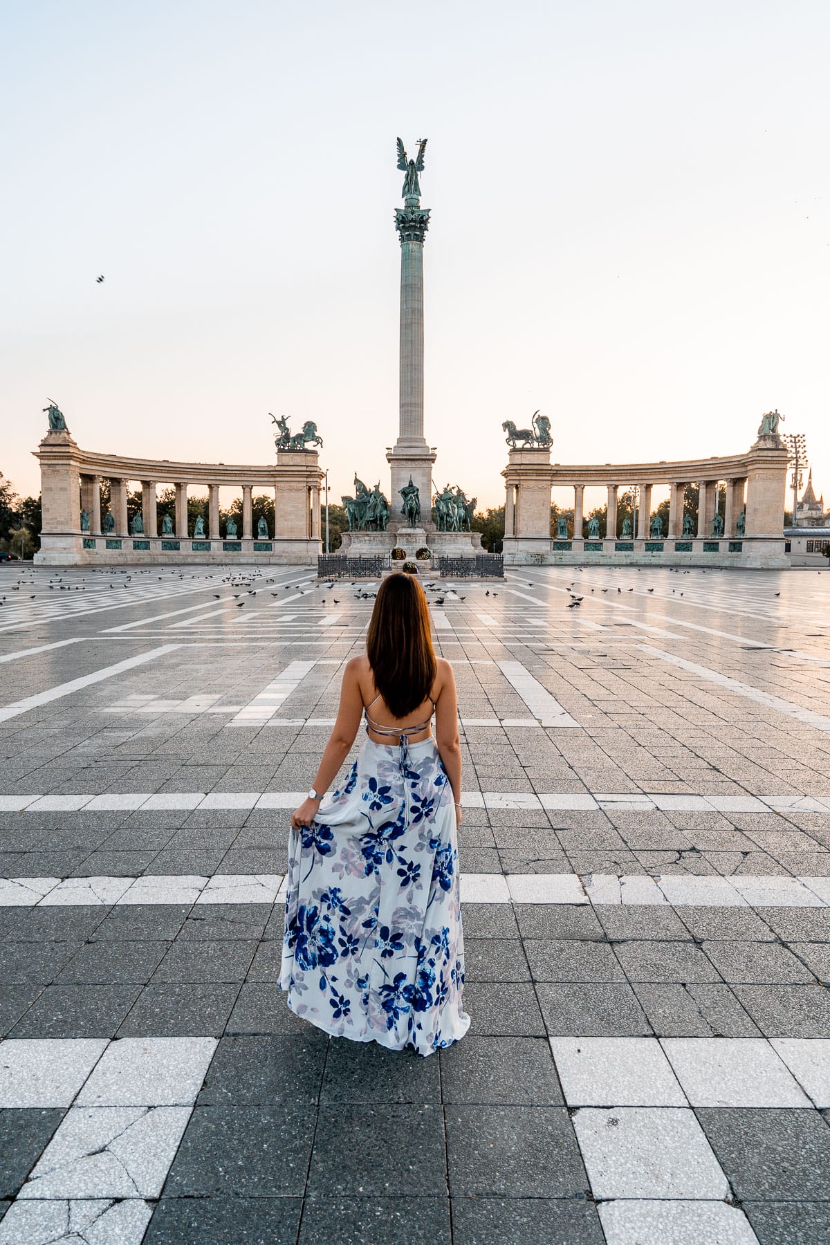 Girl in a blue floral dress standing in the middle of the Heroes Square in Budapest