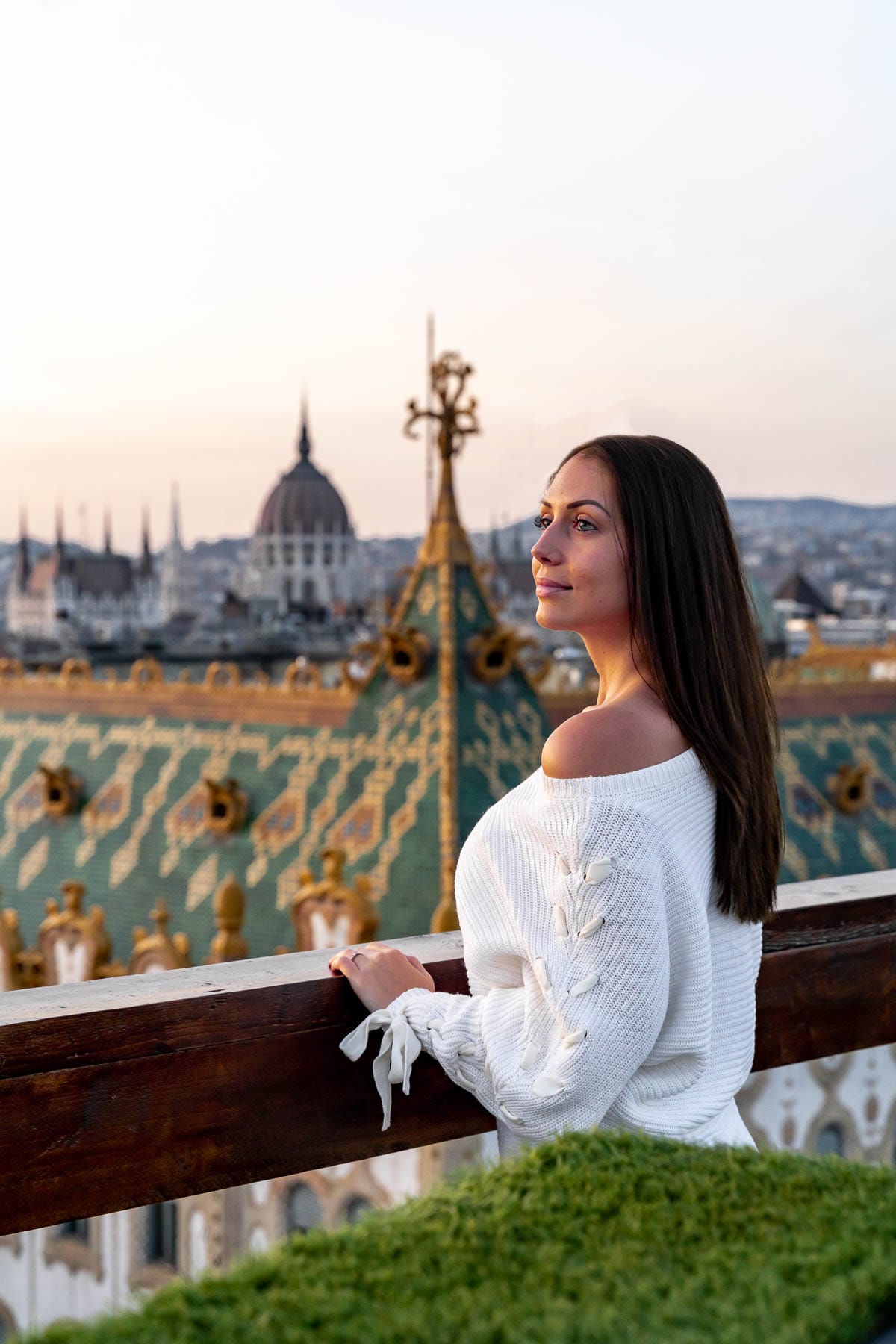 Girl in a white sweater standing at the Intermezzo Roof Terrace with the Hungarian Parliament in the background