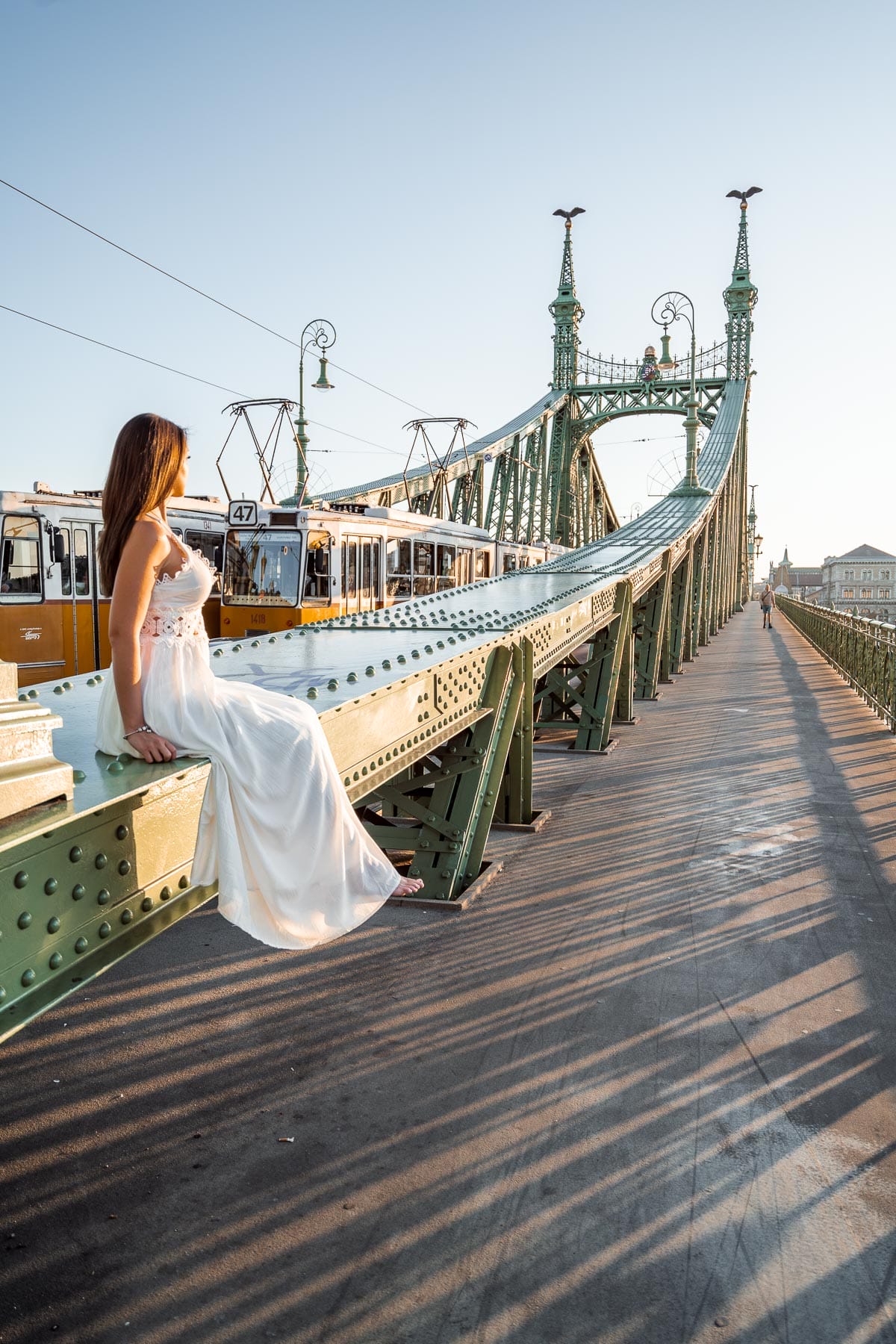 Girl in a white dress sitting on the Liberty Bridge in Budapest