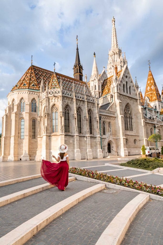Girl in a red skirt standing in front of Matthias Church in Budapest