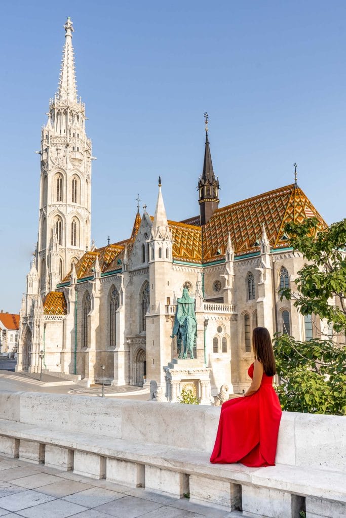 Girl in a red dress sitting in front of the Matthias Church in Budapest