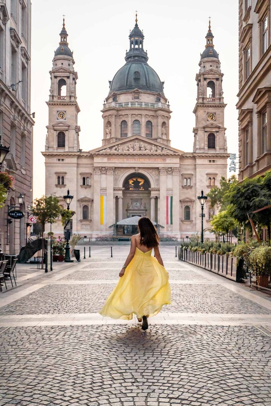 Girl in a yellow dress running towards the St. Stephen's Basilica in Budapest