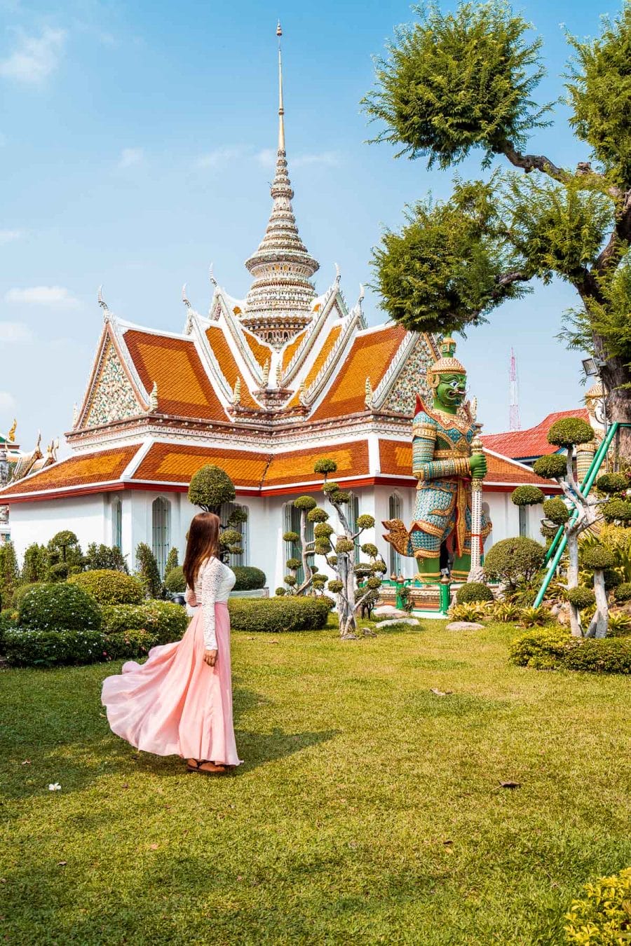 Girl in a pink dress standing in front of the entrance of Wat Arun