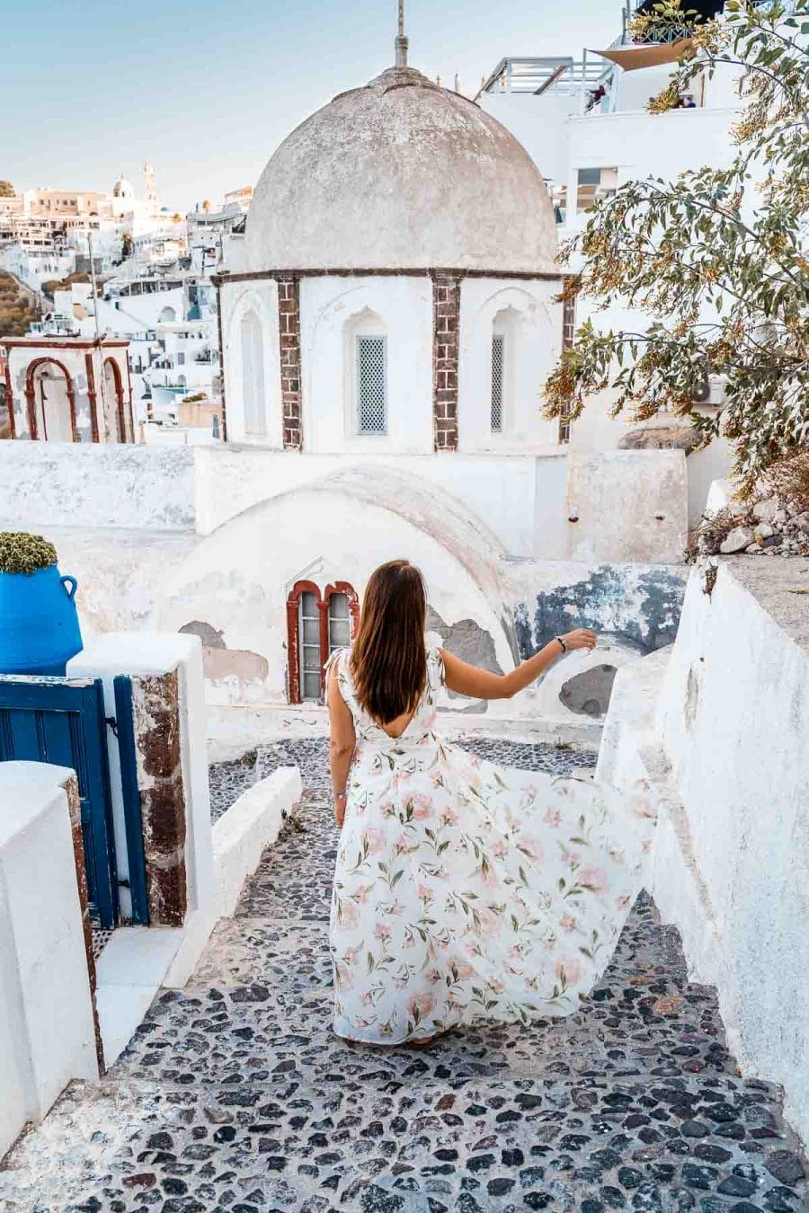 Girl in a floral dress standing in front of the church of St. John in Fira, Santorini