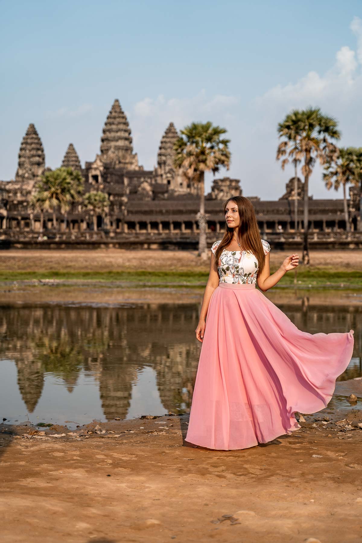 Girl in a pink skirt standing in front of the Angkor Wat in Cambodia