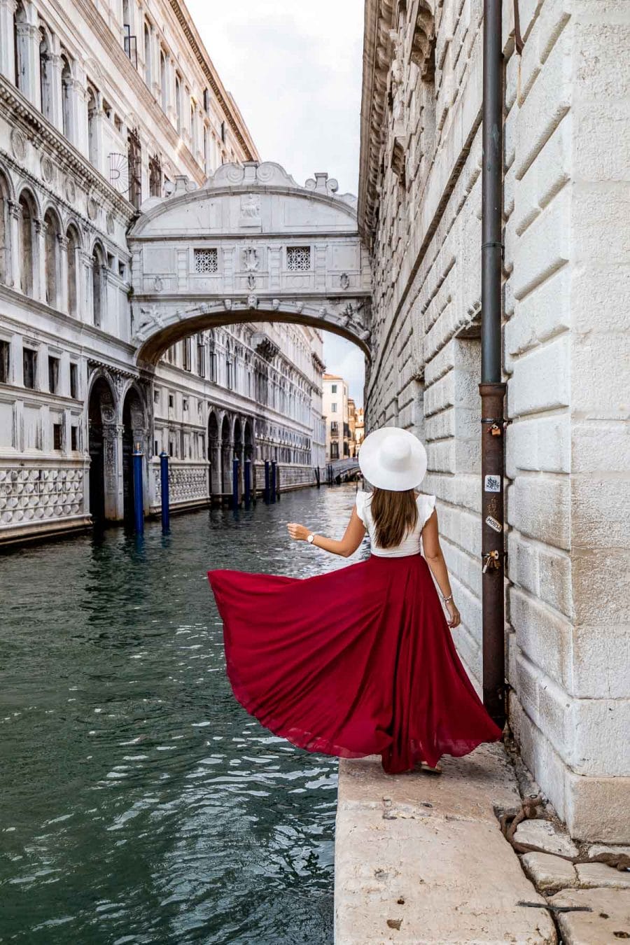 Girl in a red skirt standing below the Bridge of Sighs in Venice, Italy