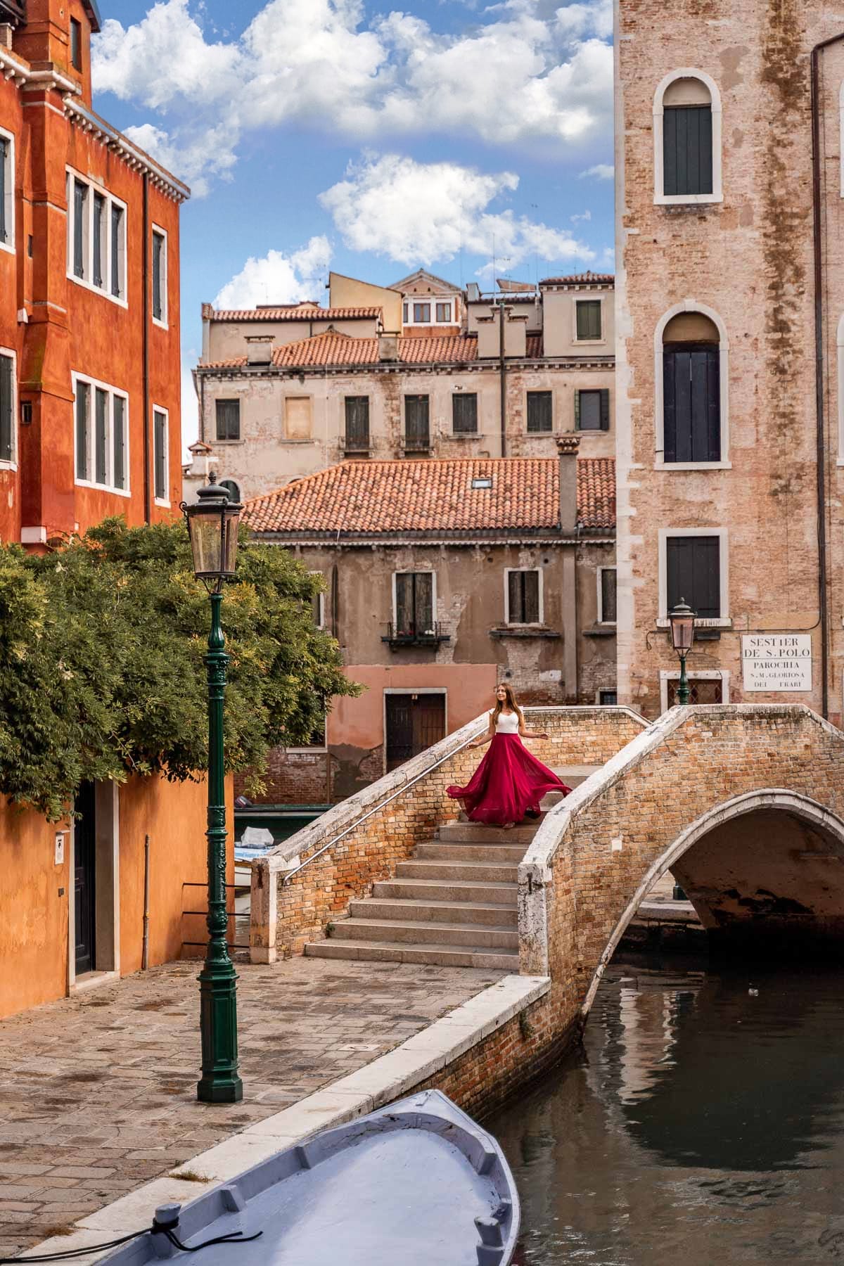 Girl in a red skirt twirling on a bridge in front of Campo San Boldo in Venice, Italy
