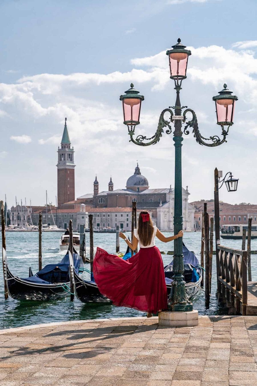 Girl in a red dress standing in front of the Gondolas at St. Mark's Square in Venice, Italy