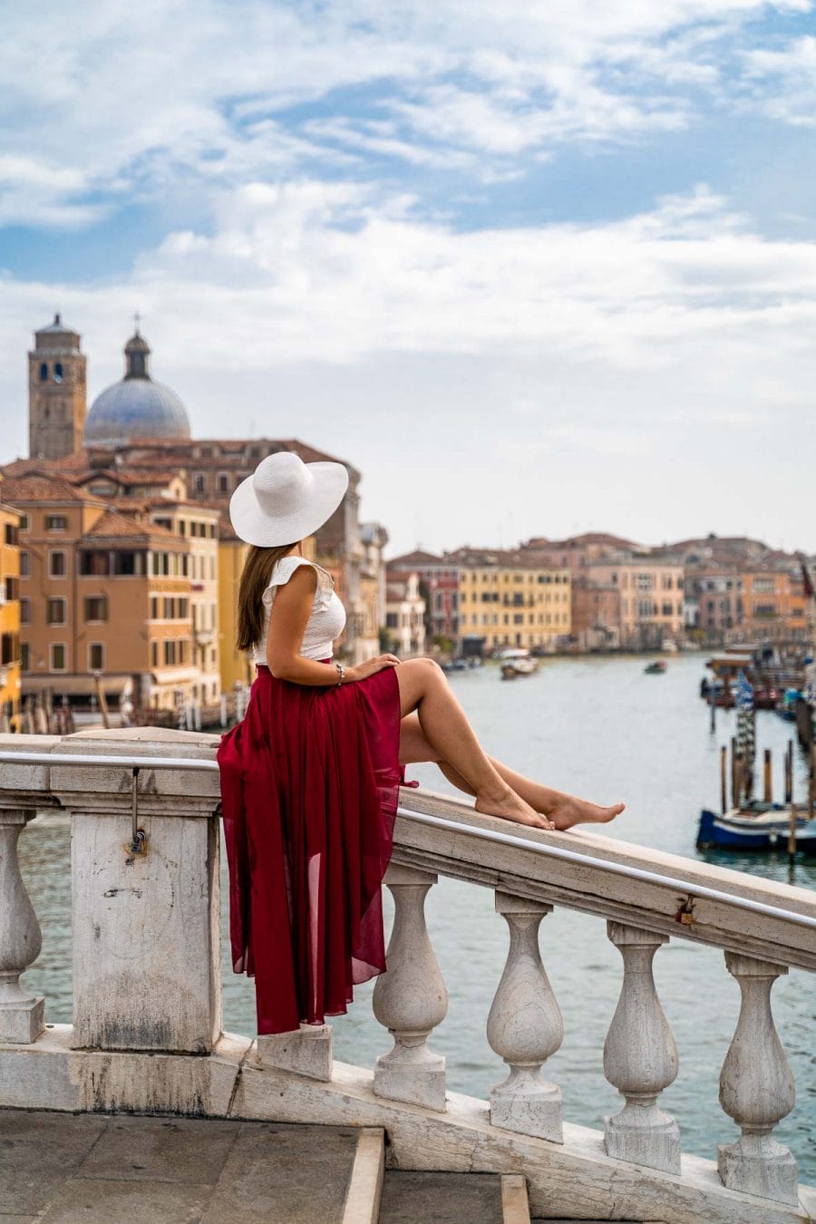 Girl in a red skirt sitting on Ponte degli Scalzi in Venice
