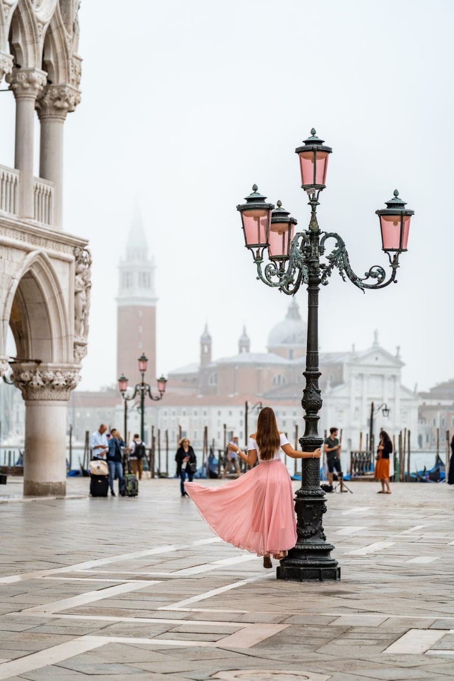 Girl in a pink skirt standing in the middle of Piazza San Marco in Venice, Italy