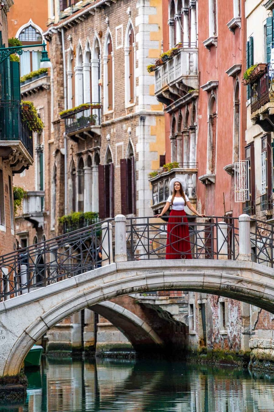 Girl in a red skirt standing on a bridge over the canals of Venice