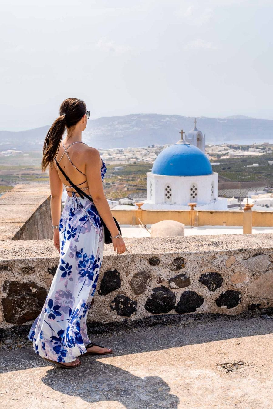 Girl in a floral dress standing on top of Pyrgos Castle in Santorini