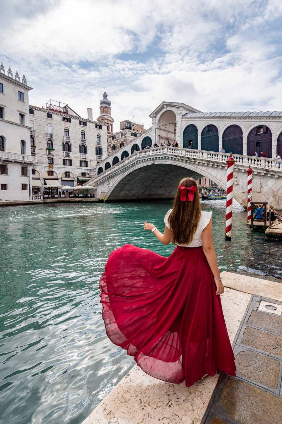 Girl in a red dress twirling in front of Rialto Bridge, which is one of the best Venice Instagram spots