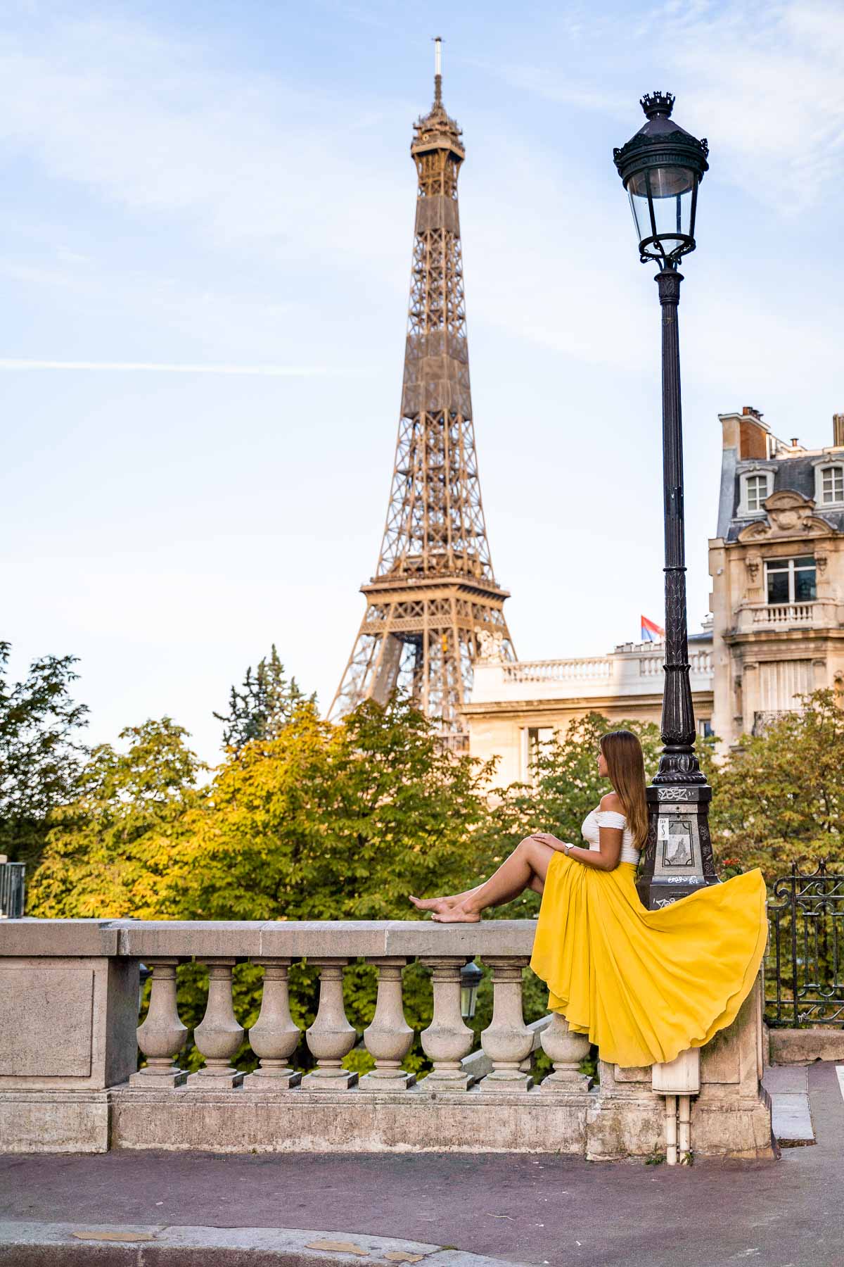 Girl in a yellow skirt sitting in front of the Eiffel Tower at Avenue de Camoens, Paris
