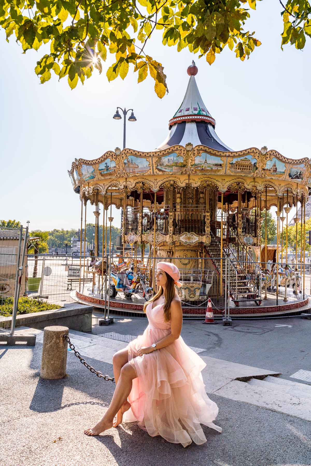 Girl in a pink dress sitting in front of a carousel near Trocadero in Paris