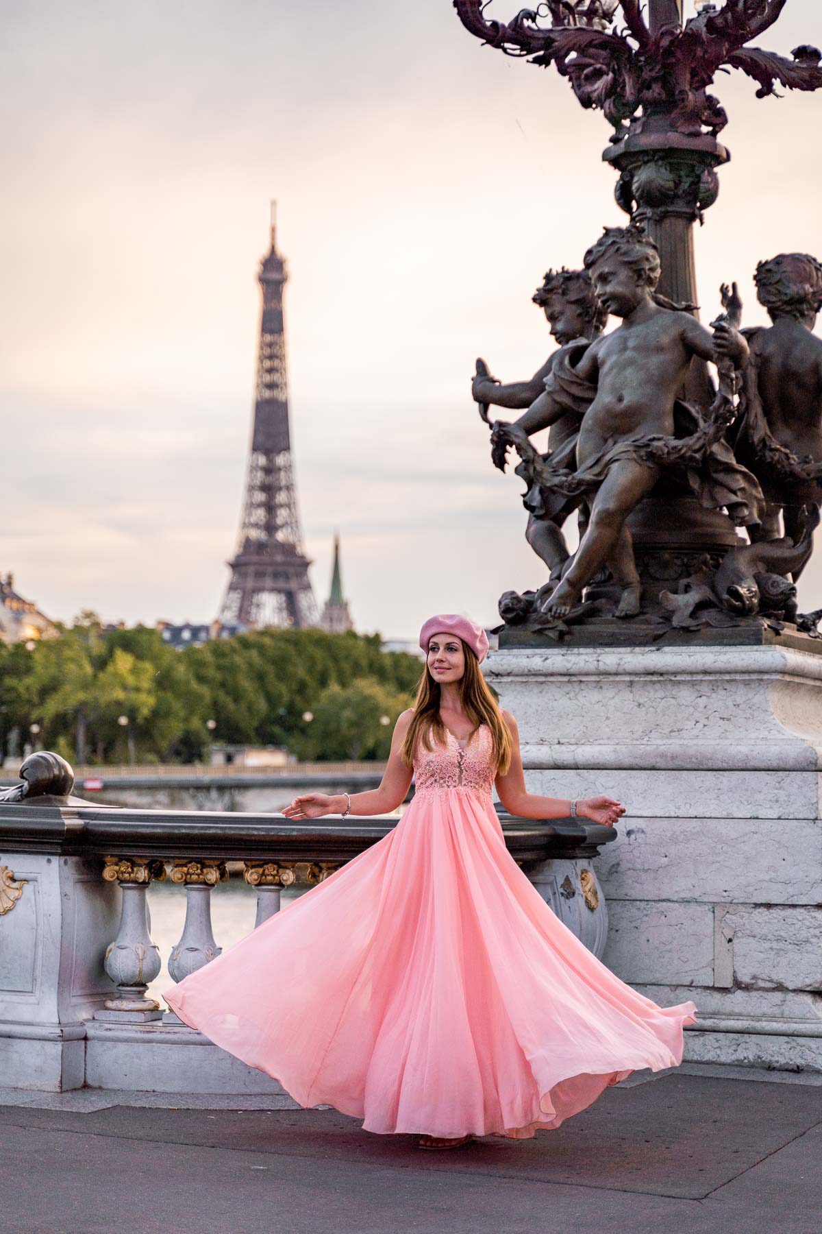 Girl in a pink dress twirling on Pont Alexandre III with the Eiffel Tower in the background