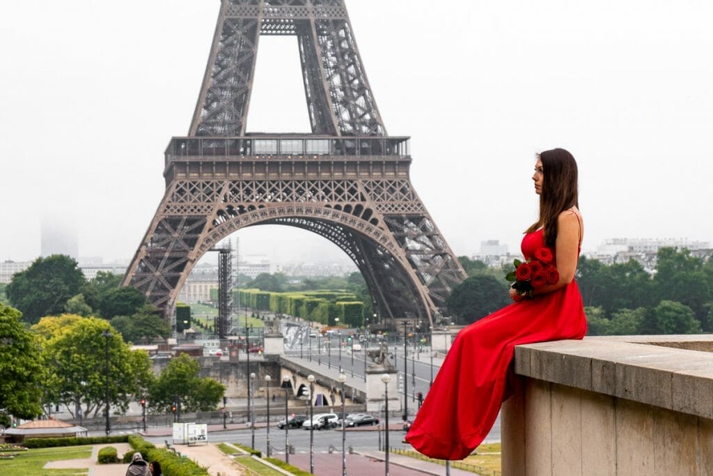 Girl in a red dress sitting at Trocadero in front of the Eiffel Tower