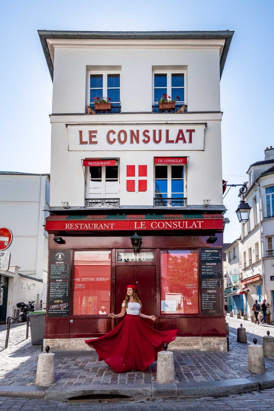 Girl in a red skirt twirling in front of Le Consulat in Montmartre, one of the best Paris Instagram Spots