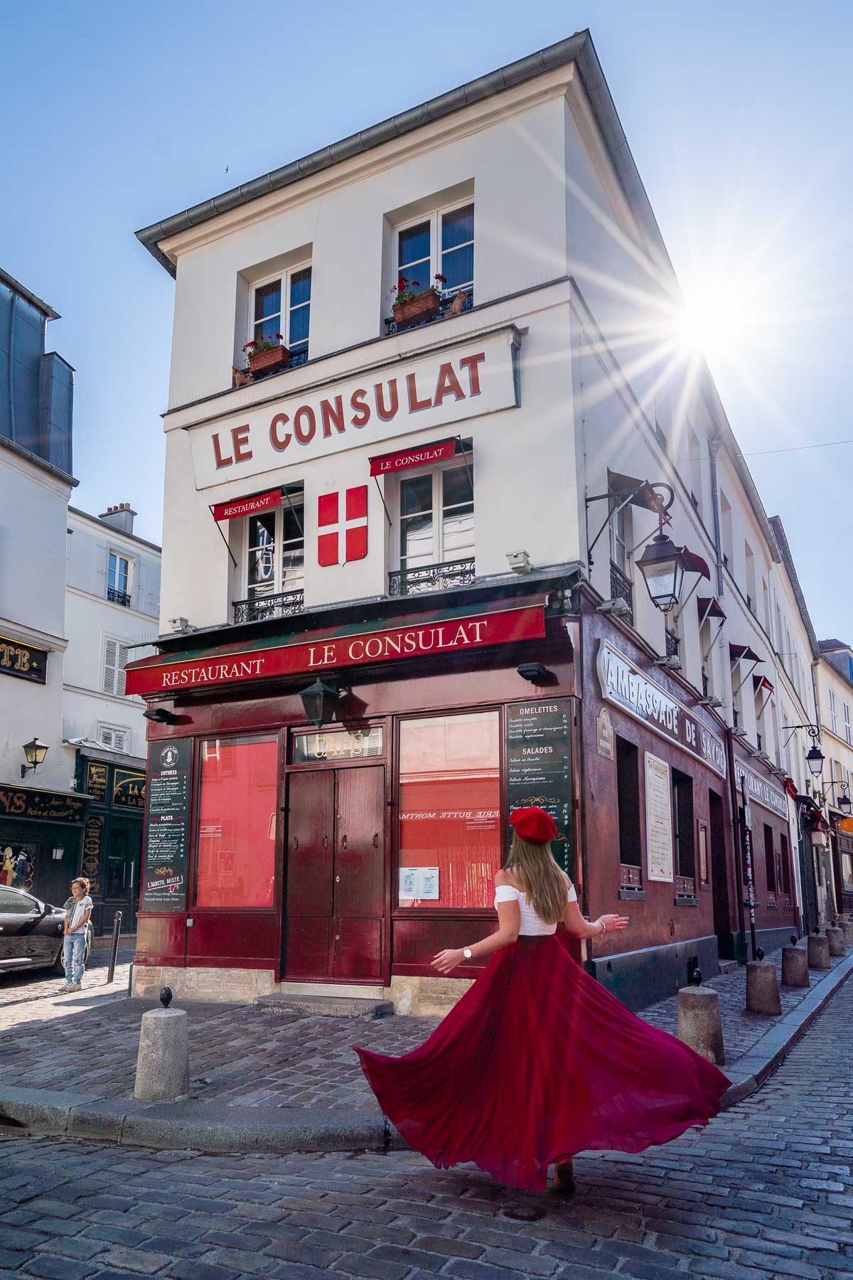 Girl in a red skirt twirling in front of Le Consulat in Montmartre, one of the best Paris Instagram Spots