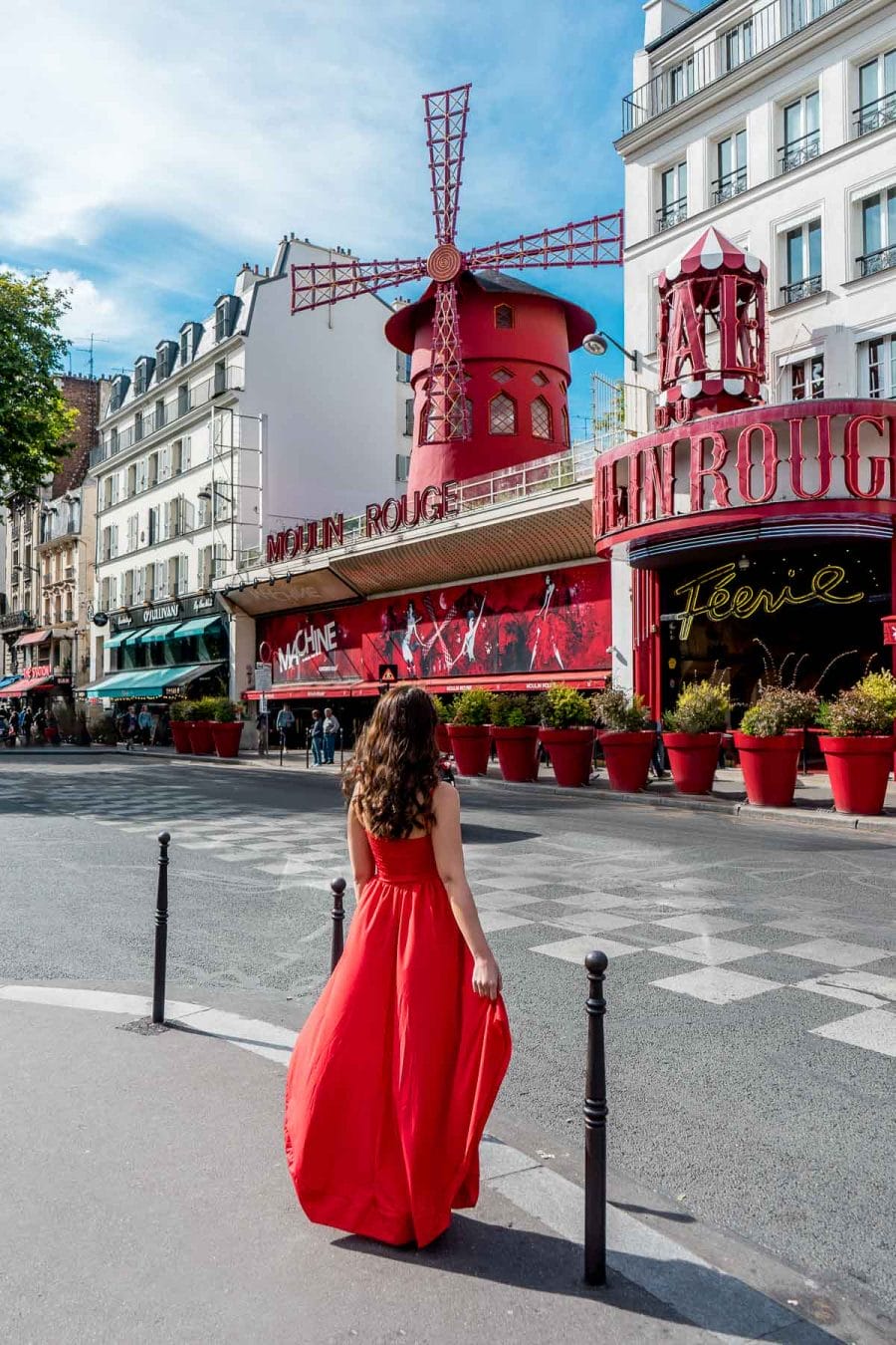 Girl in a red dress standing in front of the Moulin Rouge in Paris