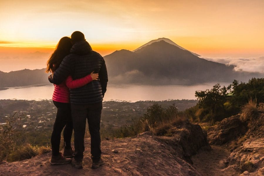 Girl and a boy watching the sunrise from Mount Batur in Bali