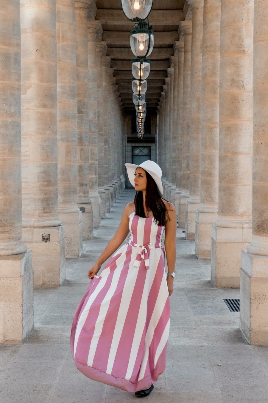 Girl in a pink-white striped dress standing in Palais Royal, one of the best Paris Instagram Spots