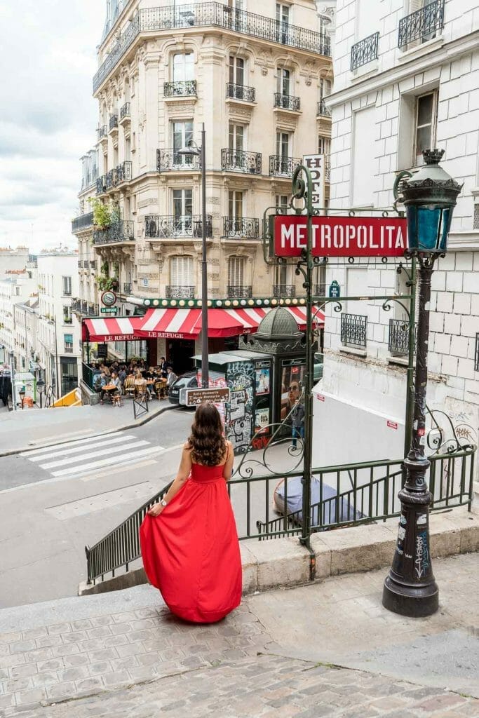 Girl in a red dress standing in front of a metro station in Paris