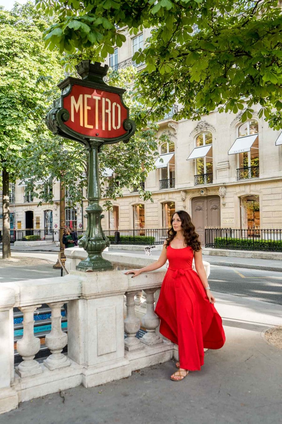 Girl in a red dress standing at a metro station sign in Paris, France