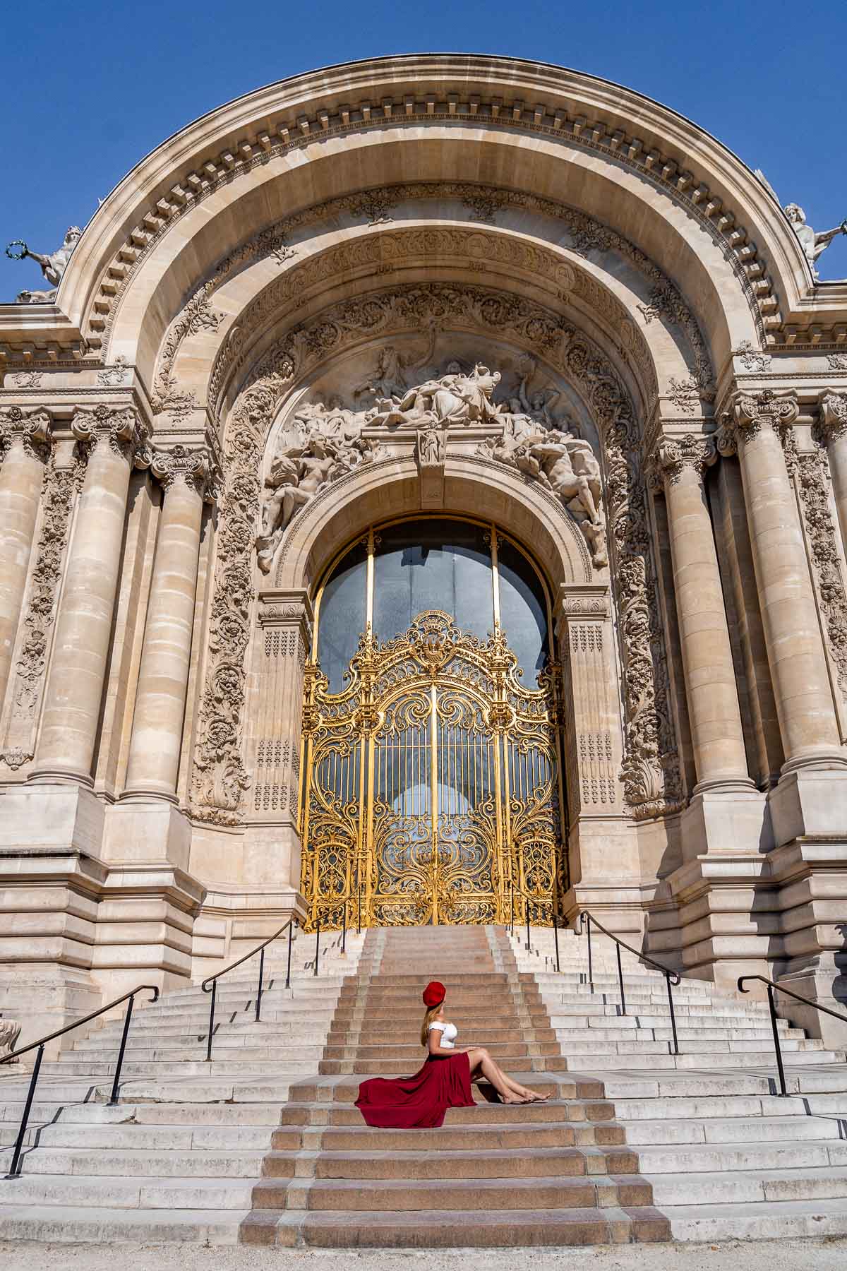 Girl in a red skirt sitting in front of Petit Palais in Paris