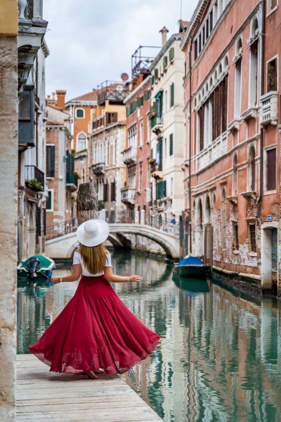 Girl in a red skirt twirling on a little pier along the canals in Venice