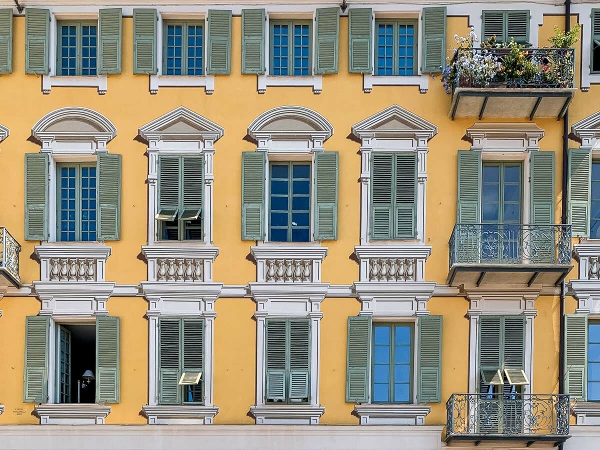Close-up photo of a yellow building with green shutters at Place Garibaldi in Nice, France