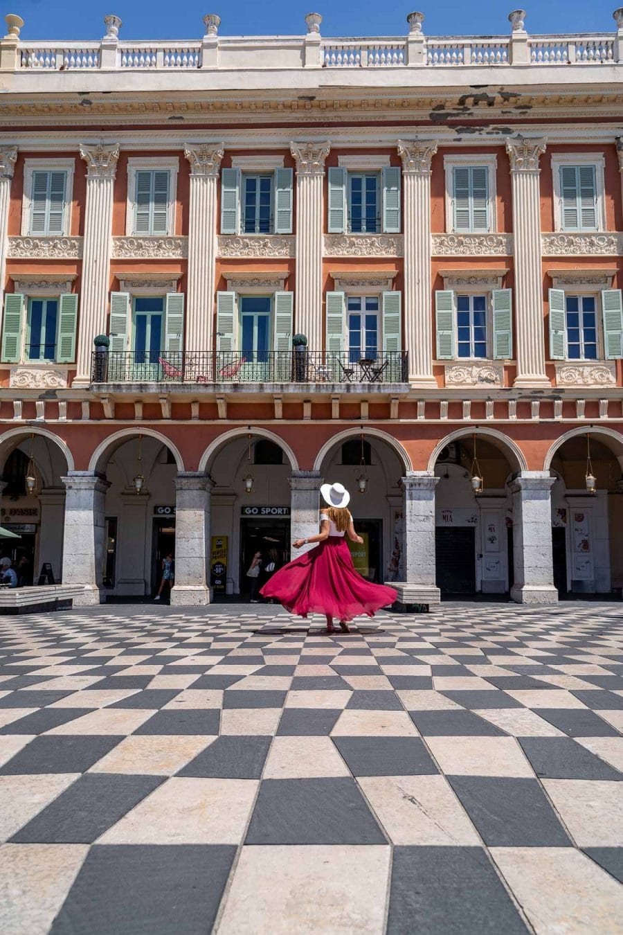 Girl in a red skirt twirling at Place Massena in Nice, France