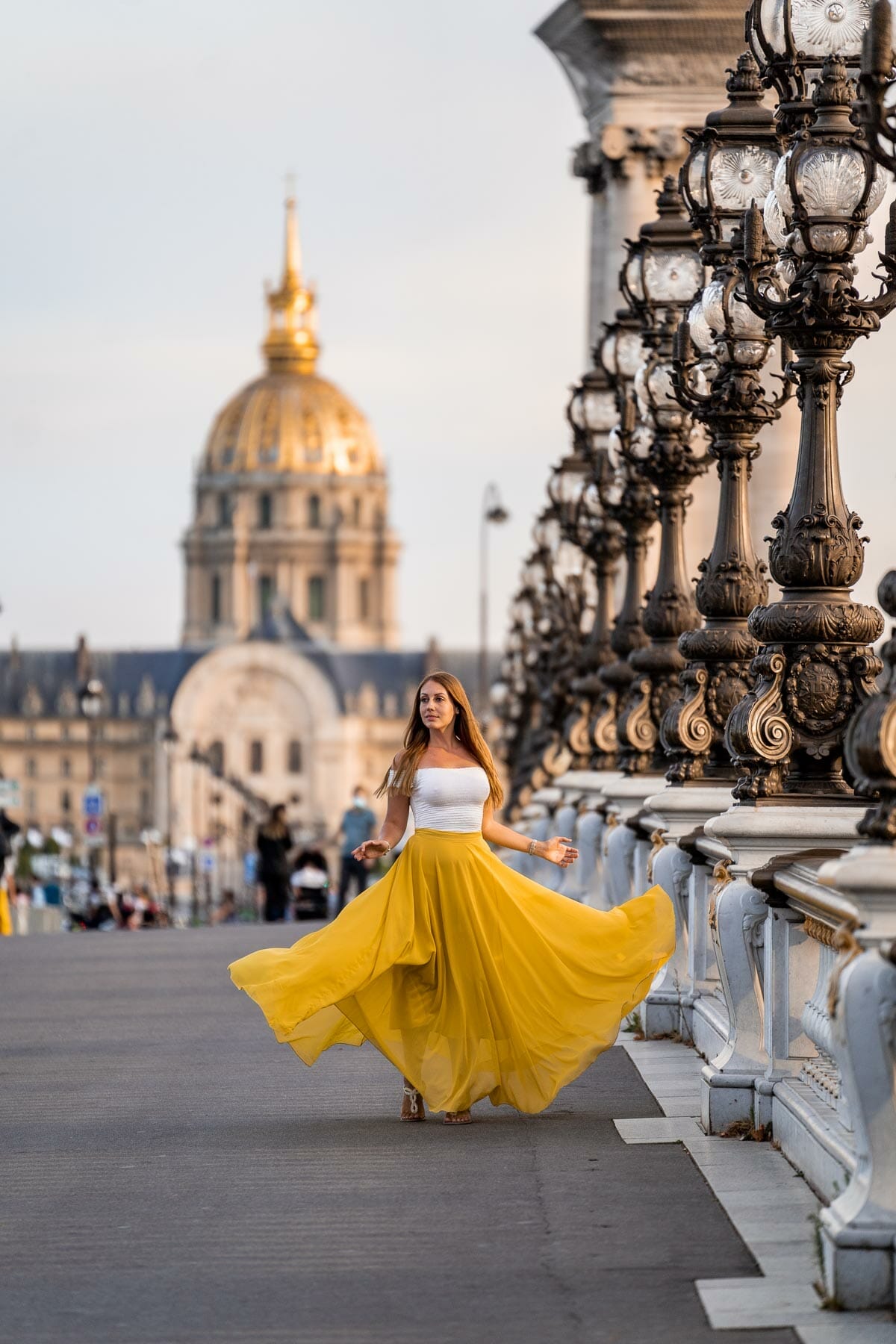 Girl in a pink dress twirling at Pont Alexandre III which is one of the most instagrammable places in Paris