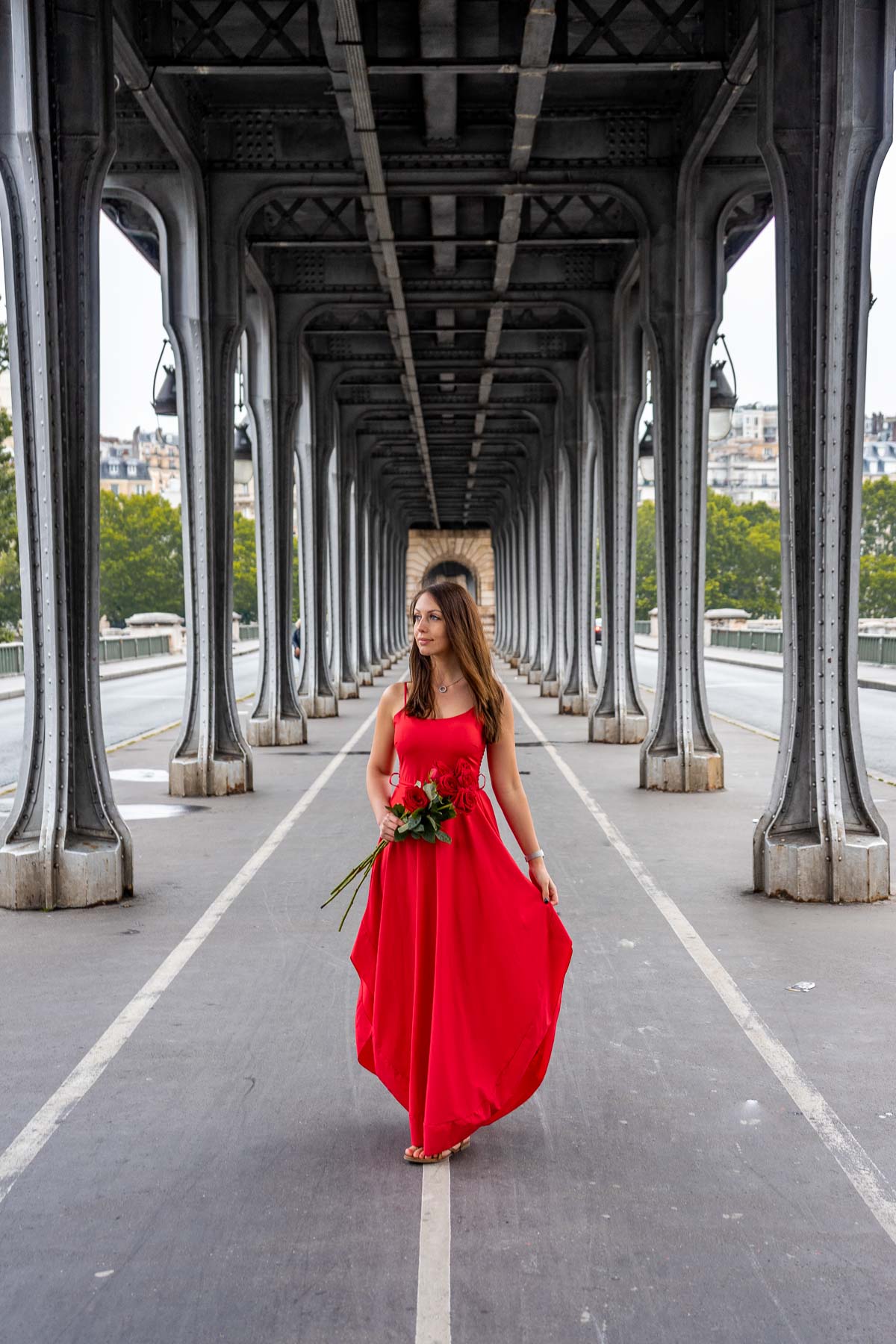 Girl in a red dress standing in the middle of Pont de bir-Hakeim with roses in her hand