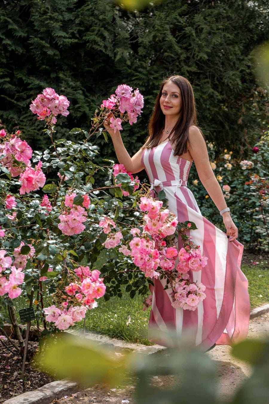 Girl in a pink dress standing in the rose garden at Jardin des Plantes in Paris