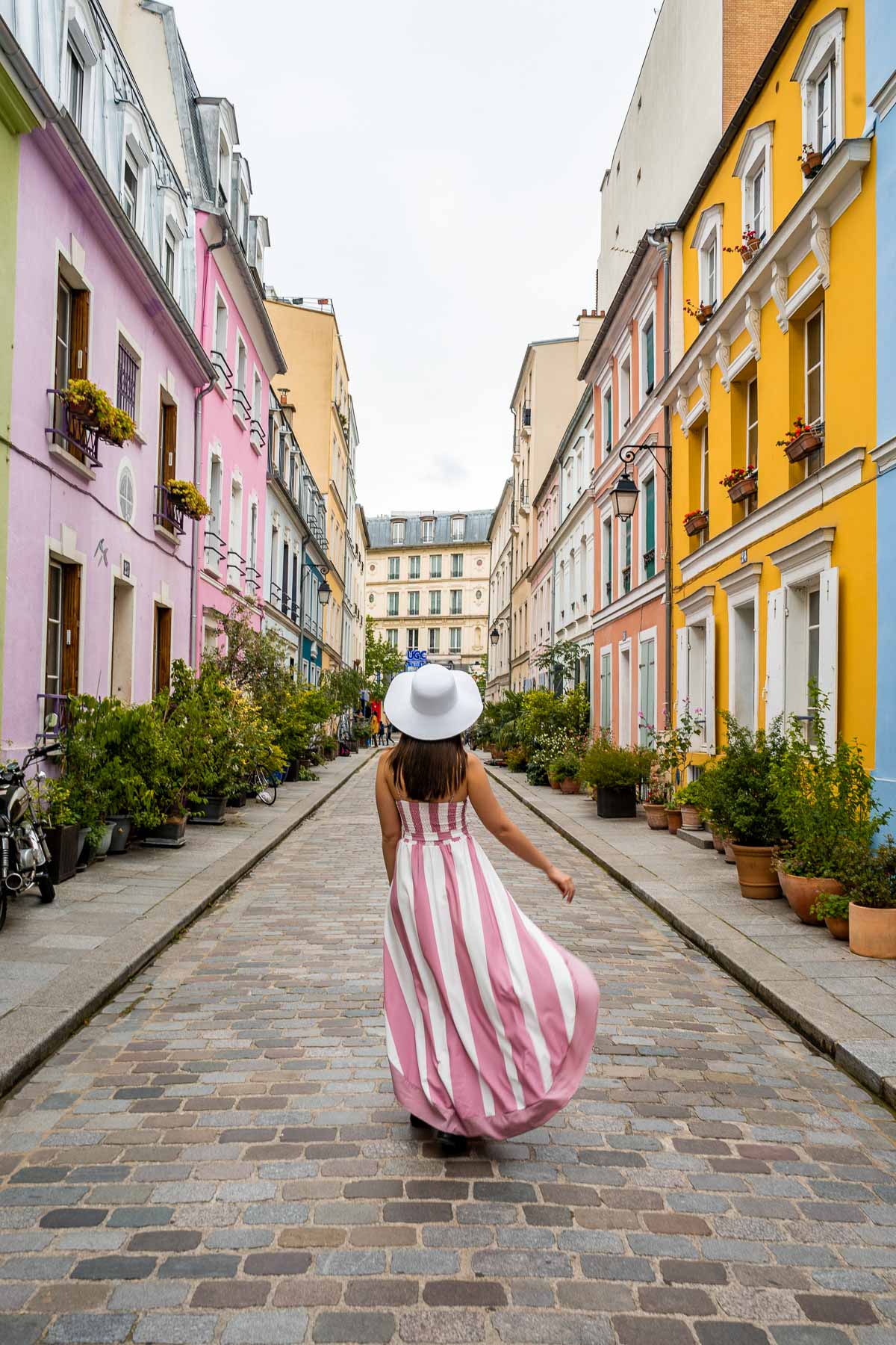 Girl in a pink-white dress twirling in the middle of Rue Crémieux in Paris, France