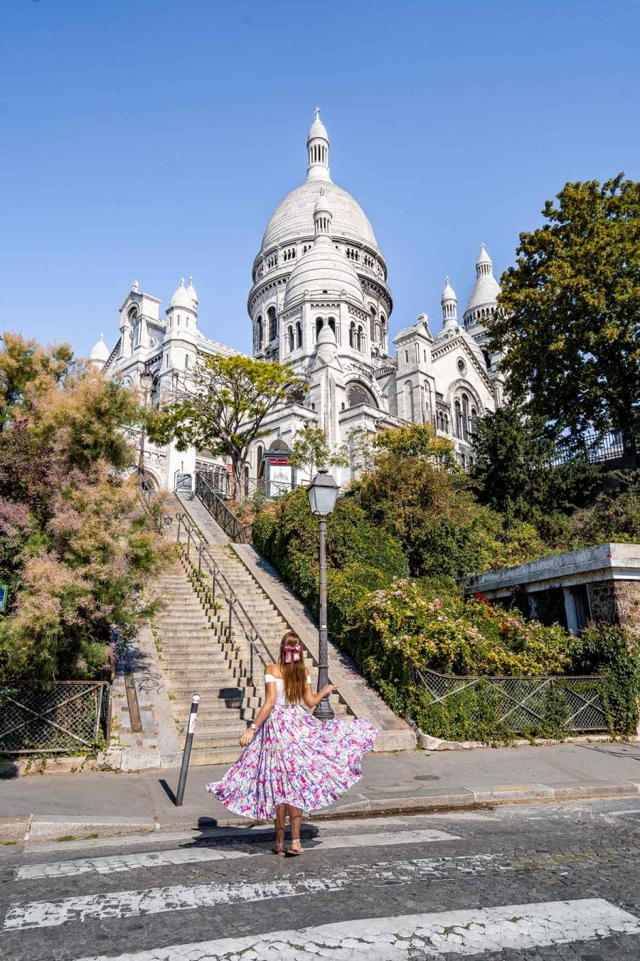 Girl in a pink floral skirt standing in front of the Sacré-Coeur Basilica in Paris