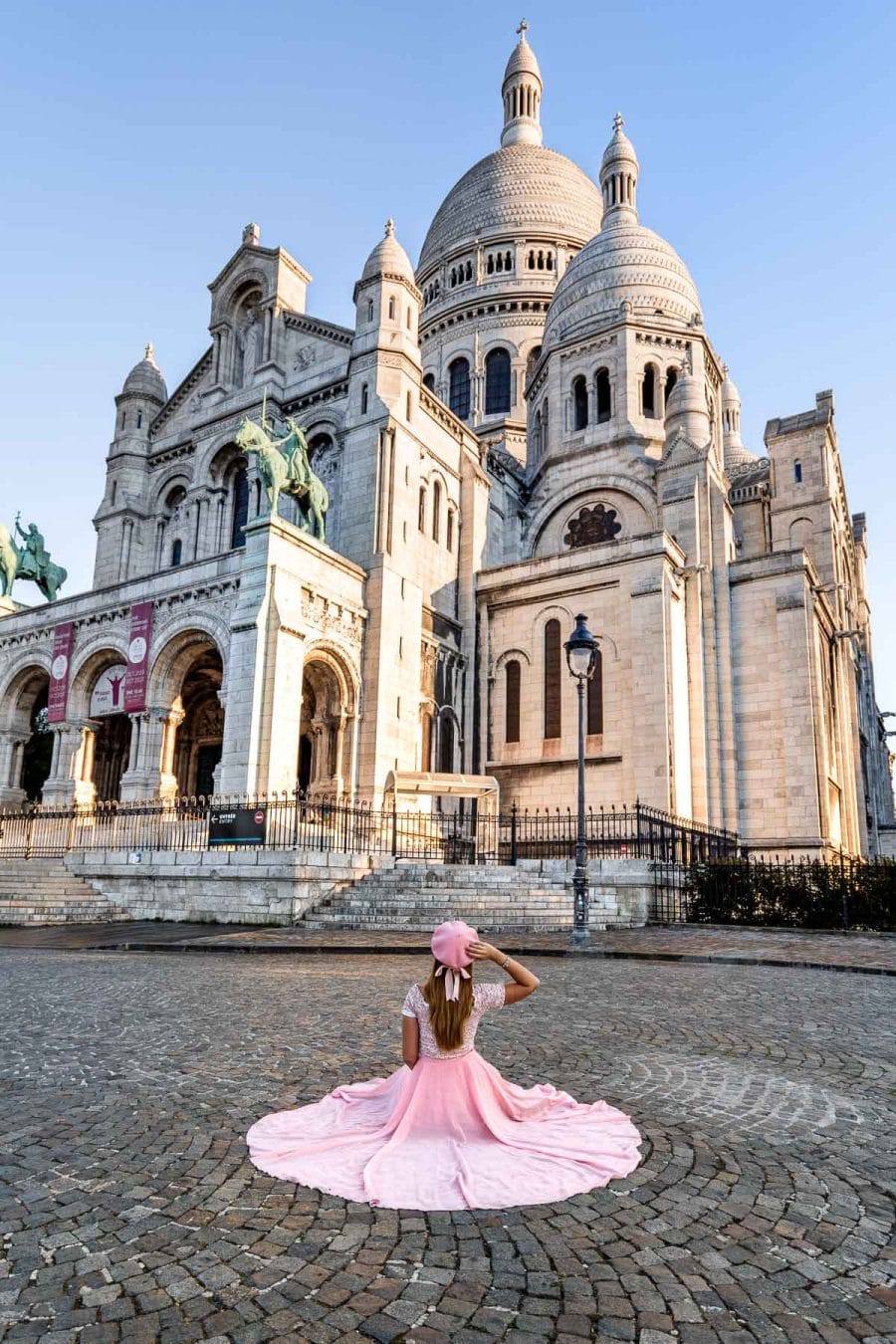 Girl in a pink dress sitting in front of the Sacré-Coeur Basilica in Paris