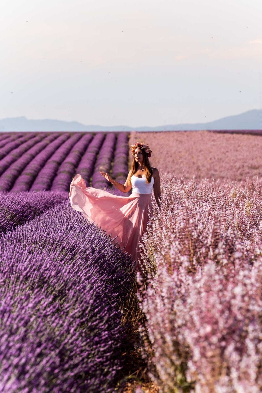 Girl in a pink skirt standing between the lavender fields and sage fields in Provence
