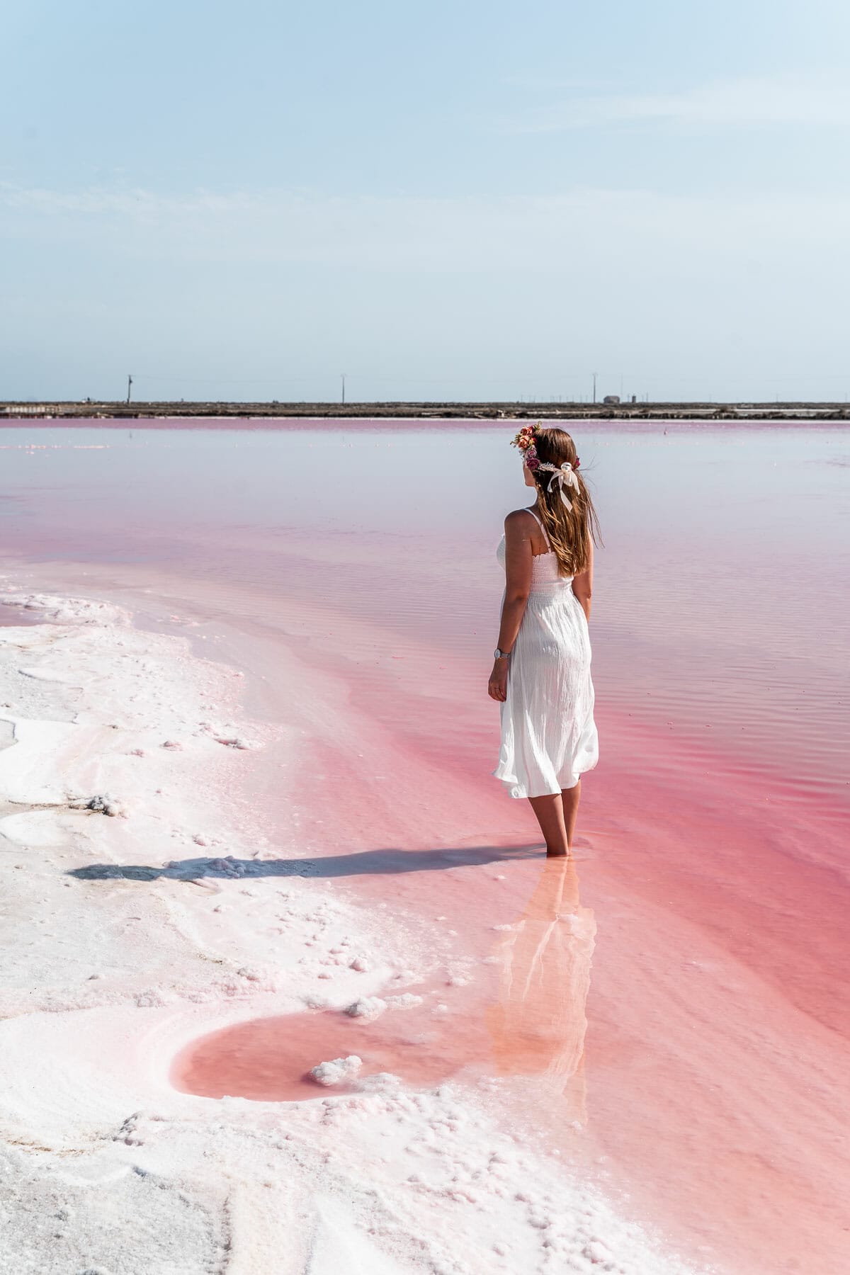Girl in a white dress standing in a pink lake in France