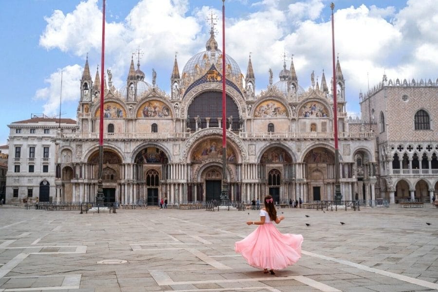 Girl in a pink dress twirling in front of the St. Marks Basilica in Venice, Italy