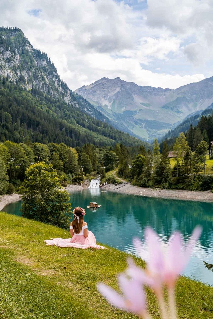 Girl in a pink skirt sitting on the shores of Stausee Steg in Liechtenstein