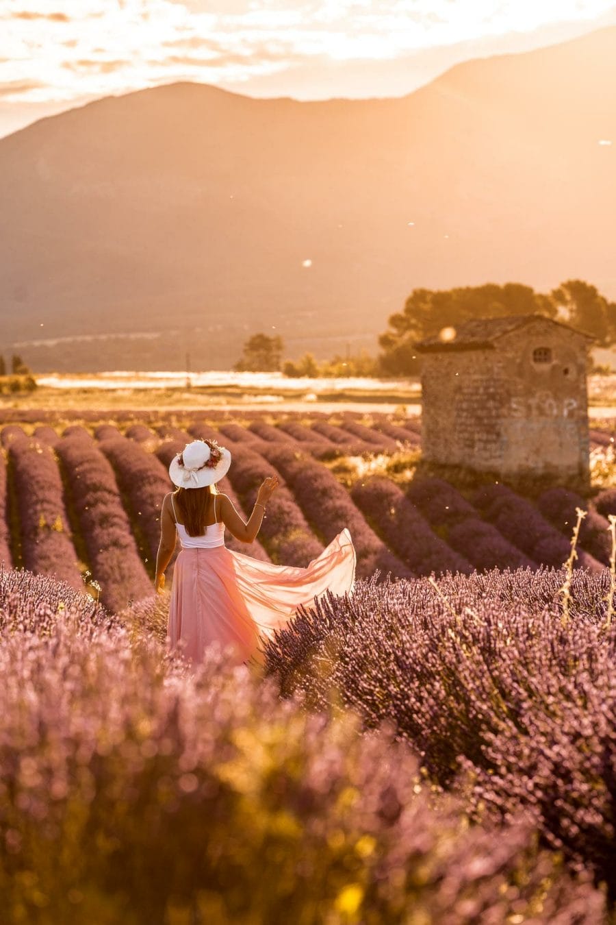 Girl in a pink skirt standing in the lavender fields in Provence at sunrise