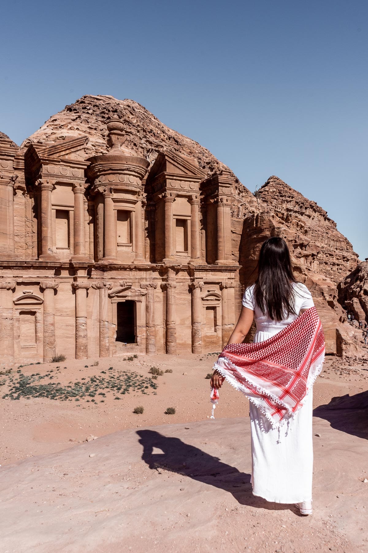 Girl in a white dress standing in front of the Ad Deir Monastery in Petra, Jordan
