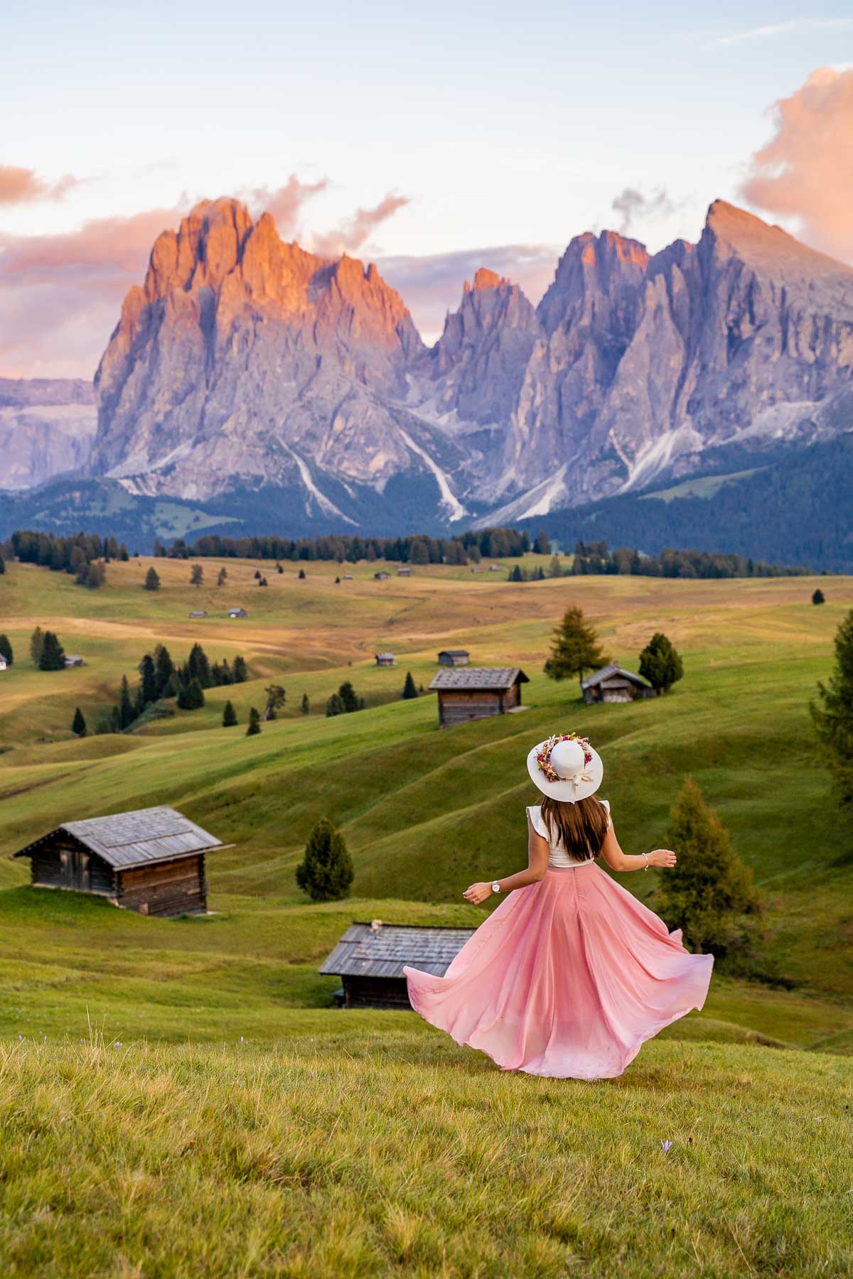 Girl in a pink skirt twirling at the meadows of Alpe di Siusi in the Dolomites