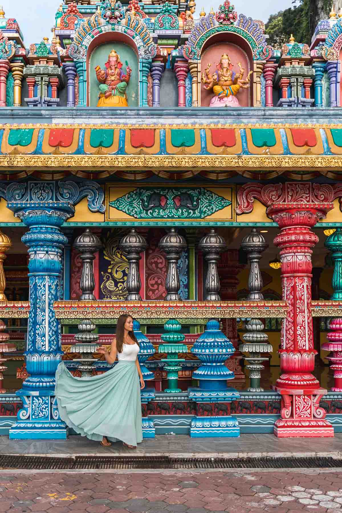 Girl in a blue skirt standing in front of the colorful columns at the Batu Caves in Kuala Lumpur, Malaysia