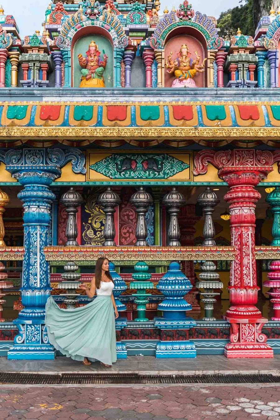 Girl in a blue skirt standing in front of the colorful columns at the Batu Caves in Kuala Lumpur, Malaysia